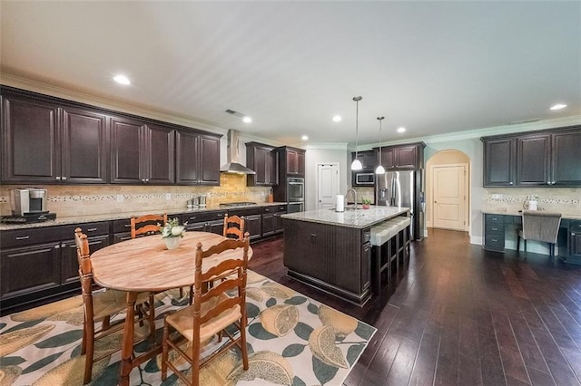 265 Enfield Ln, Mcdonough, GA 30252 - kitchen with wall chimney range hood, arched walkways, crown molding, appliances with stainless steel finishes, and dark brown cabinets