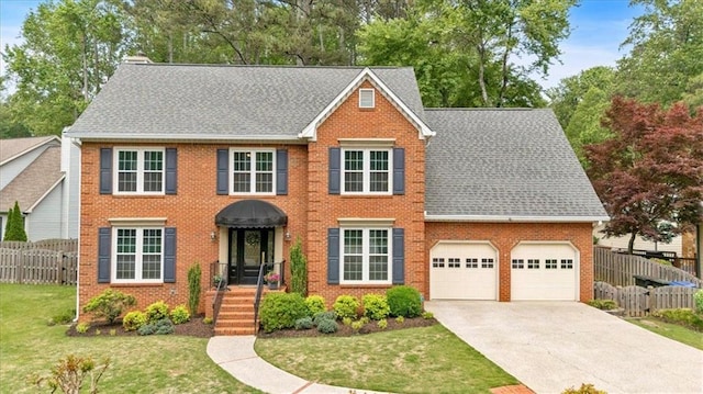 colonial inspired home with brick siding, a garage, fence, and a front lawn