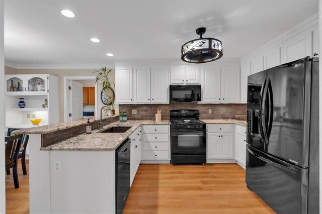 kitchen with a sink, decorative backsplash, black appliances, and white cabinetry