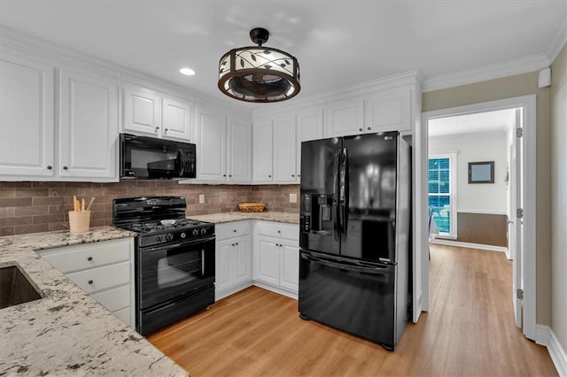 kitchen featuring white cabinets, crown molding, black appliances, and light wood-type flooring