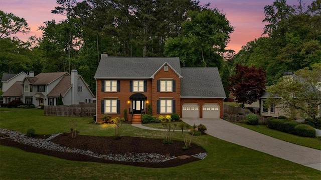 colonial house featuring a garage, a front lawn, fence, brick siding, and driveway