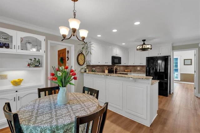 kitchen with crown molding, white cabinetry, black appliances, a peninsula, and light wood-style flooring