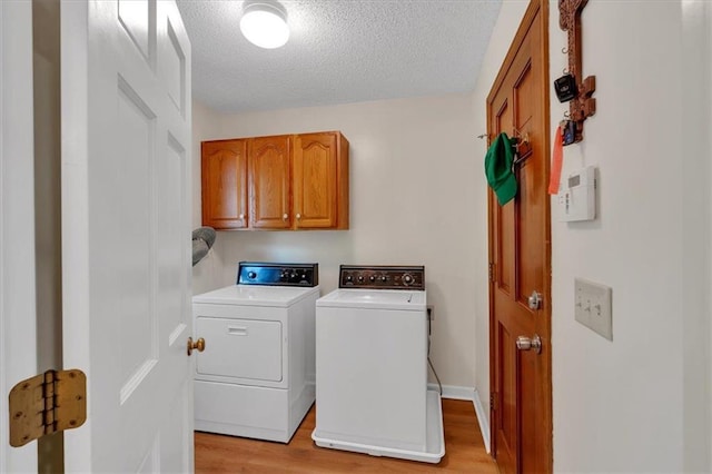 clothes washing area with cabinet space, separate washer and dryer, a textured ceiling, and light wood-style flooring