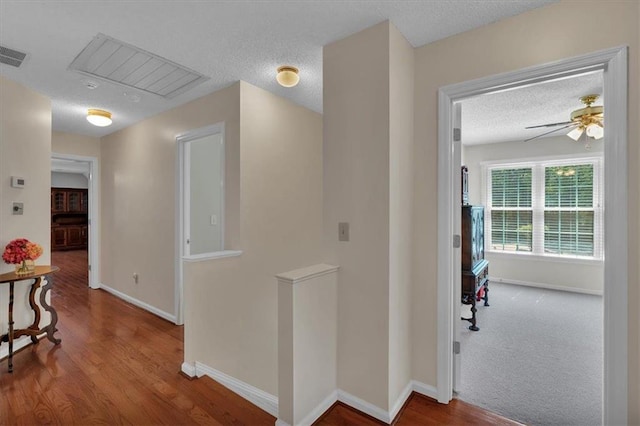 corridor featuring baseboards, a textured ceiling, and wood finished floors