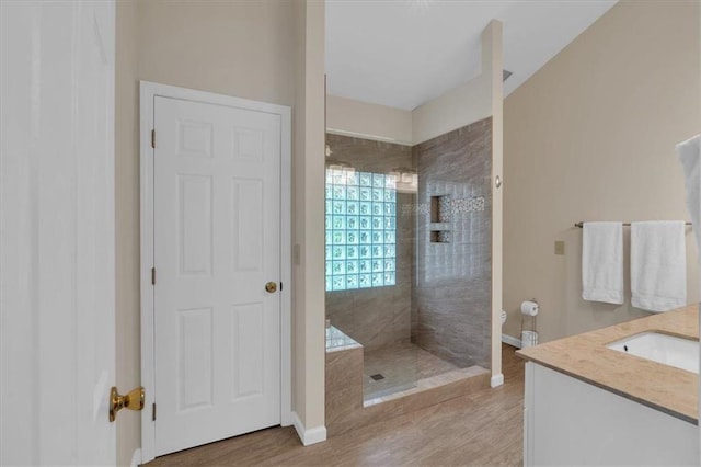 full bath featuring baseboards, a walk in shower, wood finished floors, and vanity