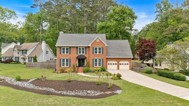colonial home with fence, driveway, a front yard, and a garage