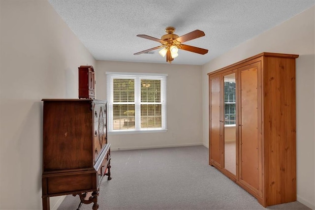 unfurnished room featuring baseboards, a textured ceiling, ceiling fan, and light carpet