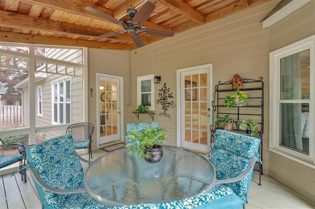 sunroom / solarium featuring ceiling fan, outdoor dining space, and beam ceiling
