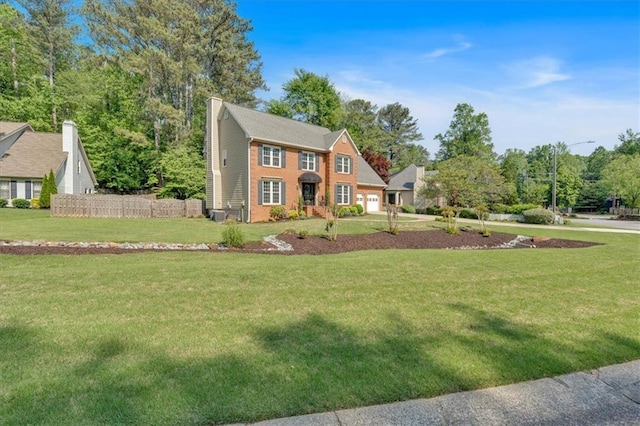 colonial-style house featuring fence, a chimney, and a front lawn