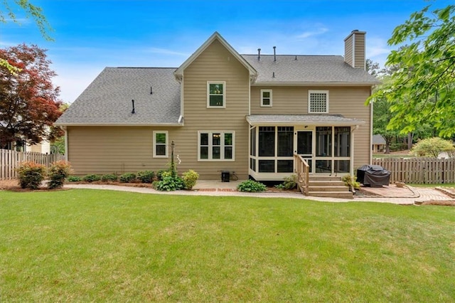 back of house featuring fence, a sunroom, a chimney, a patio area, and a yard