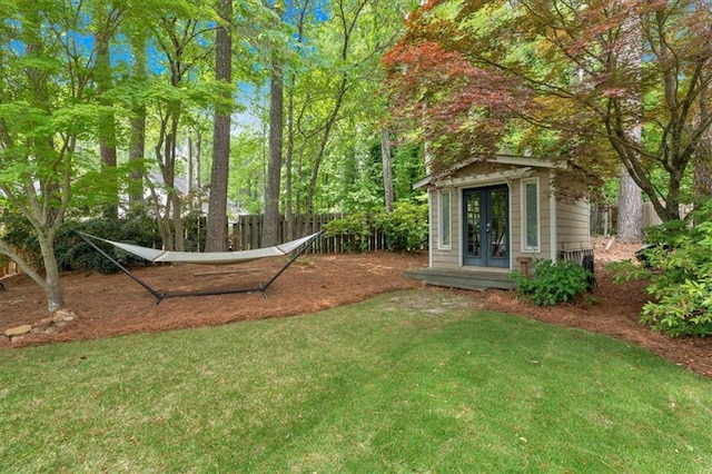 view of yard with french doors, fence, and an outdoor structure