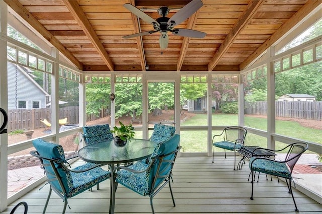 sunroom with outdoor dining area, ceiling fan, and beam ceiling