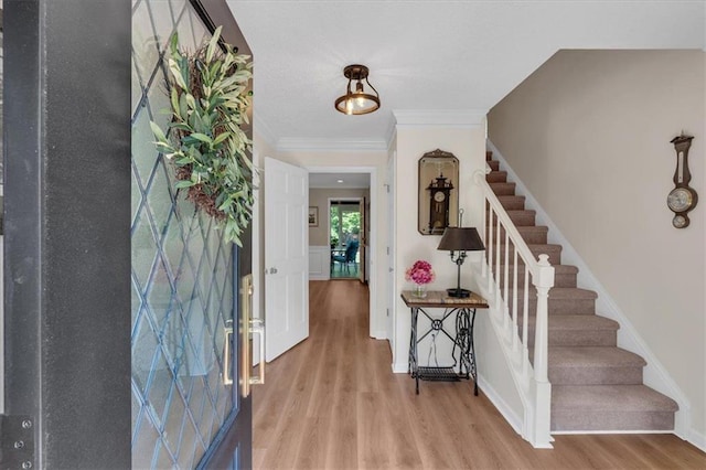 foyer entrance featuring stairway, baseboards, crown molding, and wood finished floors