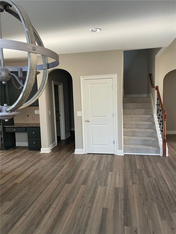 interior space featuring dark wood-type flooring, arched walkways, and baseboards