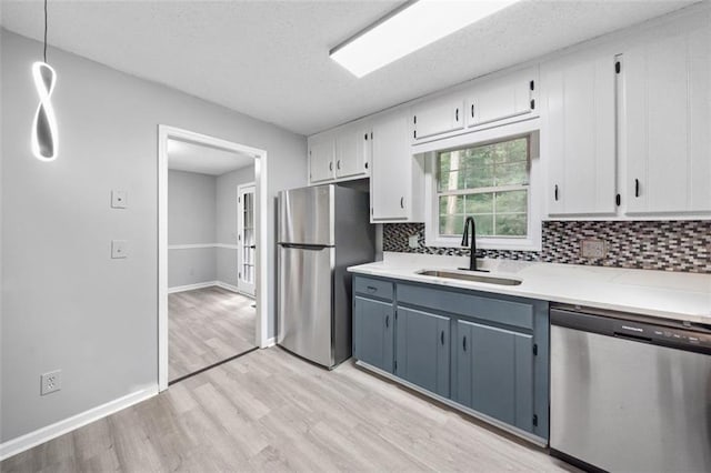 3232 Valley View St, Powder Springs, GA 30127 - kitchen featuring appliances with stainless steel finishes, light wood-style flooring, tasteful backsplash, white cabinetry, and a textured ceiling