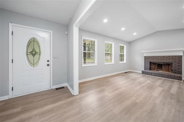 3232 Valley View St, Powder Springs, GA 30127 - entrance foyer featuring light wood-style floors, vaulted ceiling, a brick fireplace, recessed lighting, and a textured ceiling