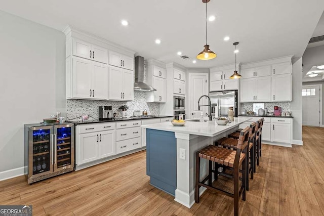 123 Rabun Ct, Hoschton, GA 30548 - kitchen featuring wall chimney exhaust hood, wine cooler, stainless steel appliances, light wood-style floors, and recessed lighting