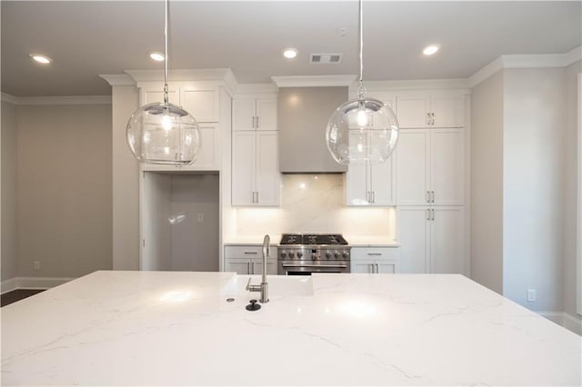 kitchen with pendant lighting, light stone counters, white cabinets, and stainless steel range