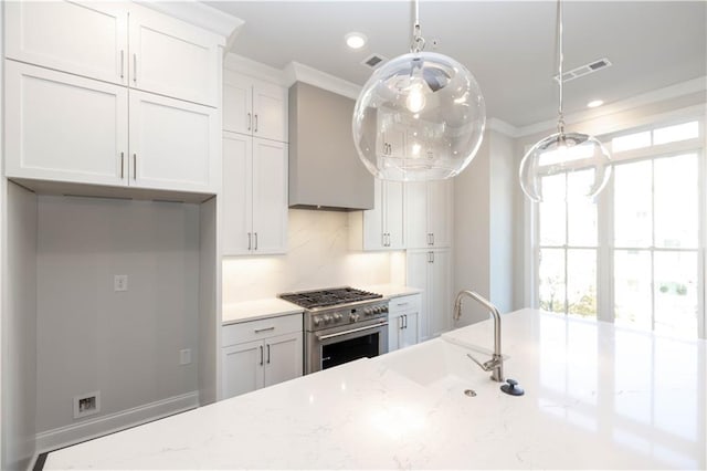 kitchen featuring white cabinetry, light stone counters, crown molding, stainless steel stove, and custom exhaust hood