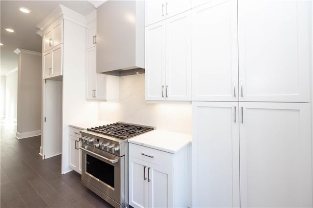 kitchen featuring premium range hood, high end stainless steel range oven, dark hardwood / wood-style floors, tasteful backsplash, and white cabinetry