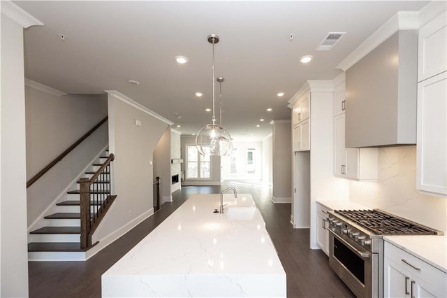 kitchen with pendant lighting, dark hardwood / wood-style floors, an island with sink, and stainless steel stove