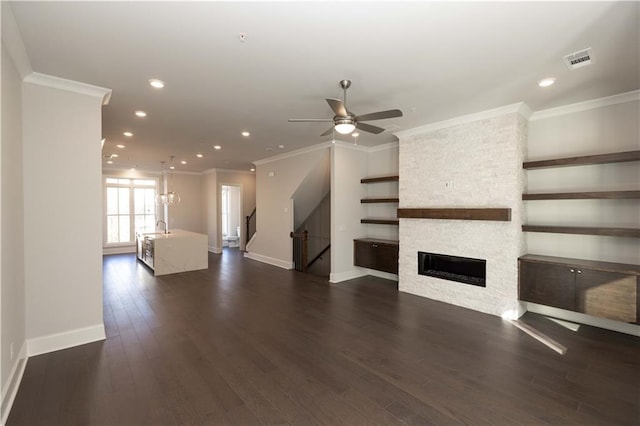 unfurnished living room featuring dark hardwood / wood-style floors, ceiling fan, ornamental molding, and a fireplace