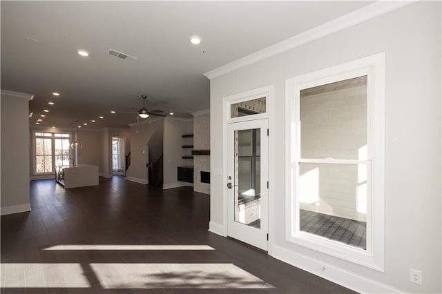 interior space with a fireplace, ornamental molding, ceiling fan, and dark wood-type flooring