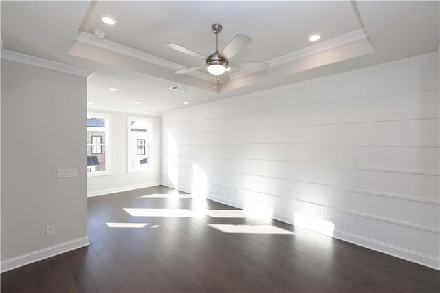 empty room featuring a raised ceiling, ceiling fan, dark hardwood / wood-style flooring, and crown molding