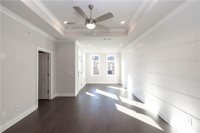 unfurnished room featuring a tray ceiling, crown molding, ceiling fan, and dark wood-type flooring