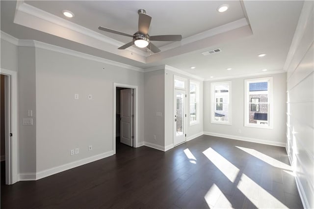 empty room with a tray ceiling, ceiling fan, dark hardwood / wood-style floors, and ornamental molding