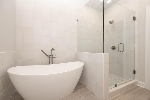 bathroom featuring plus walk in shower and tile walls