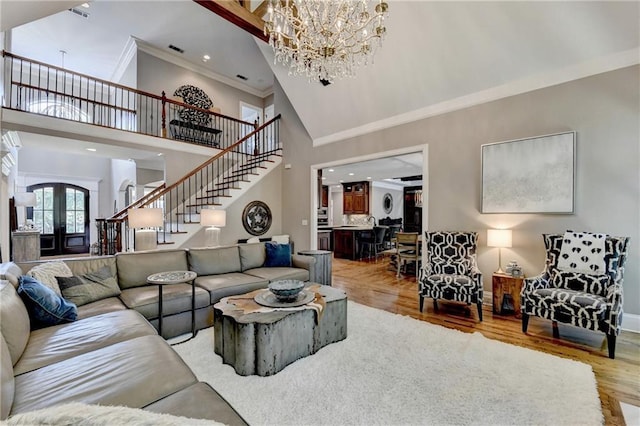 10020 Normandy Ln, Suwanee, GA 30024 - living room with stairway, a high ceiling, crown molding, light wood-style floors, and a chandelier