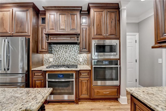 10020 Normandy Ln, Suwanee, GA 30024 - kitchen with appliances with stainless steel finishes, light wood finished floors, decorative backsplash, light stone counters, and crown molding