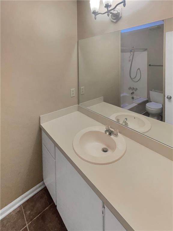 full bathroom featuring washtub / shower combination, tile patterned floors, toilet, an inviting chandelier, and vanity