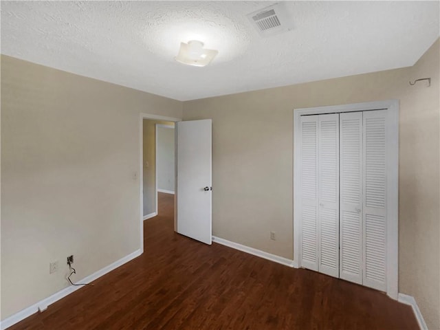 unfurnished bedroom with a closet, dark hardwood / wood-style floors, and a textured ceiling