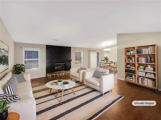 living room featuring an inviting chandelier, hardwood / wood-style flooring, a fireplace, and lofted ceiling