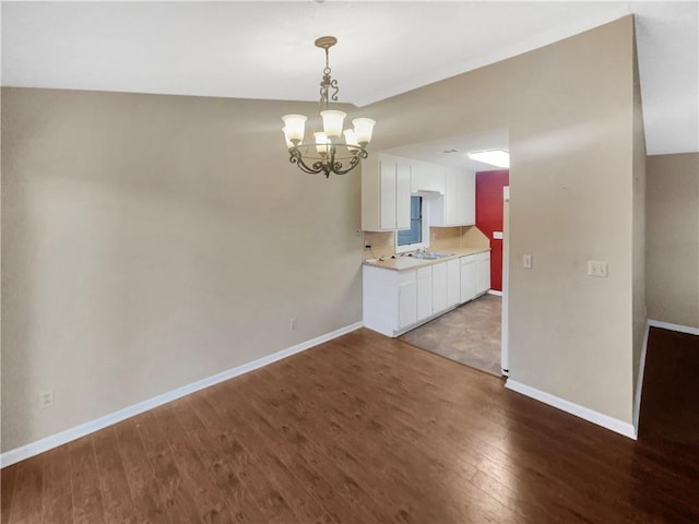 unfurnished dining area featuring sink, a chandelier, and dark hardwood / wood-style flooring