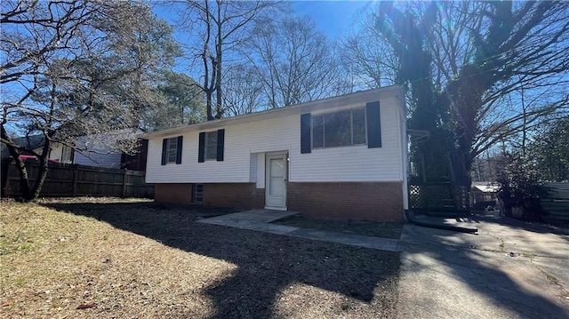 split foyer home featuring brick siding and fence