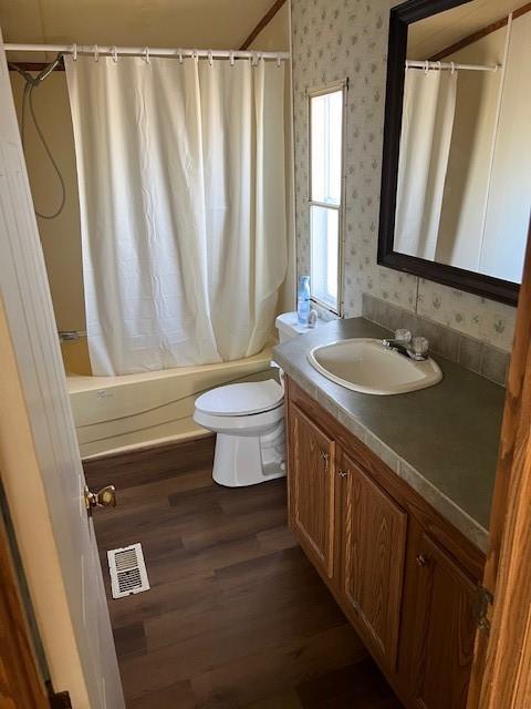 full bathroom with shower / tub combo with curtain, wood-type flooring, toilet, and vanity