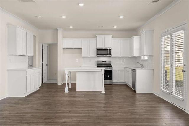 kitchen featuring stainless steel appliances, dark wood-type flooring, white cabinetry, and crown molding