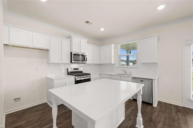 kitchen with visible vents, appliances with stainless steel finishes, a kitchen bar, white cabinetry, and a sink