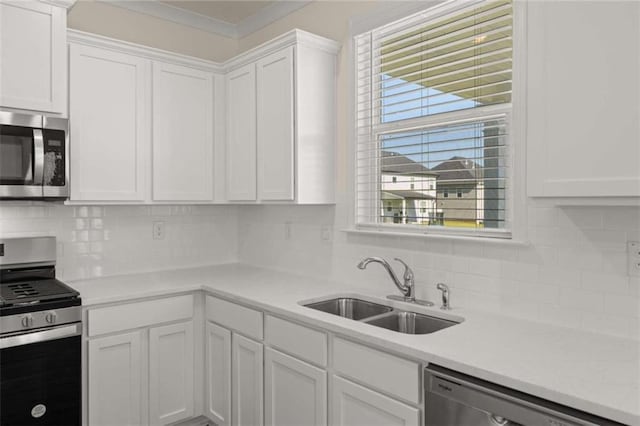 kitchen featuring stainless steel appliances, white cabinetry, a sink, and backsplash