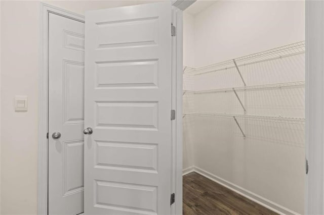 walk in closet with dark wood-type flooring