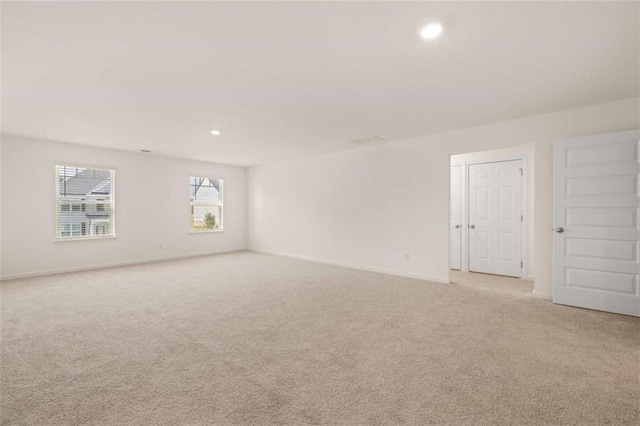 spare room with baseboards, recessed lighting, and light colored carpet