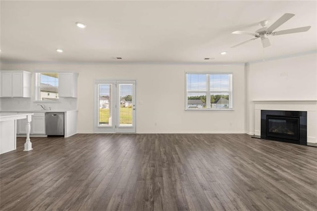 unfurnished living room featuring recessed lighting, a glass covered fireplace, dark wood finished floors, and baseboards