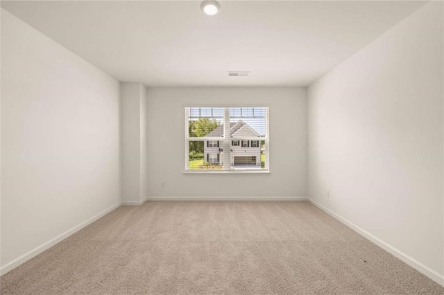 empty room featuring light colored carpet, visible vents, and baseboards