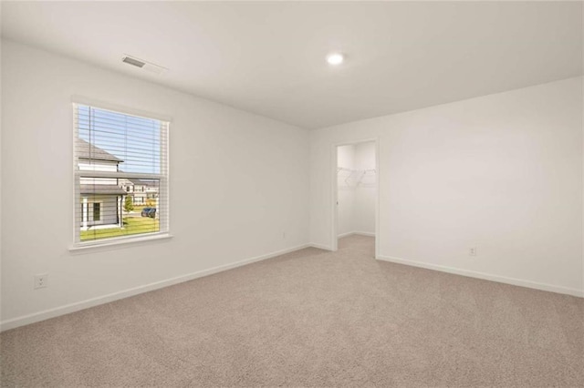 unfurnished room with baseboards, visible vents, and light colored carpet