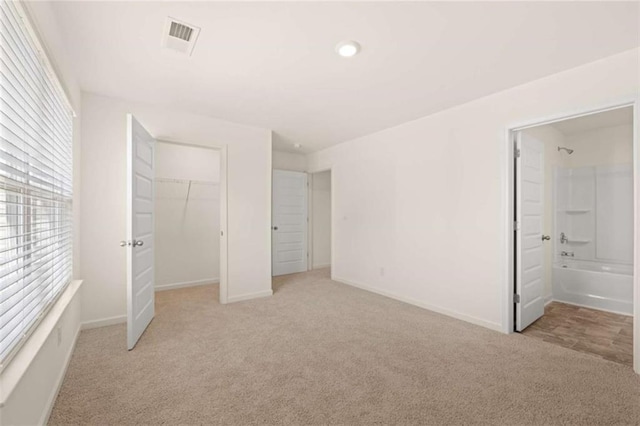 unfurnished bedroom featuring baseboards, visible vents, a closet, and light colored carpet