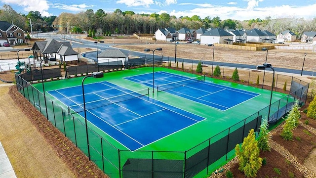 view of tennis court with a residential view and fence