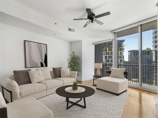 living room featuring expansive windows, ceiling fan, and light wood-type flooring